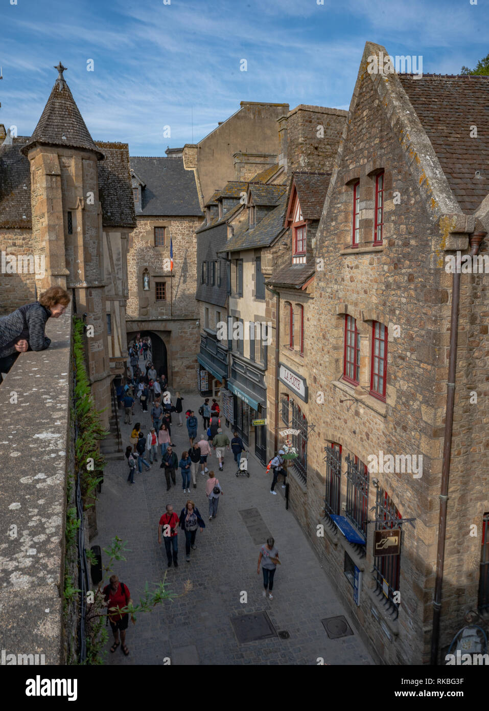 Medieval village lane and buildings on Mont St Michel with tourists waking down the lane. Stock Photo