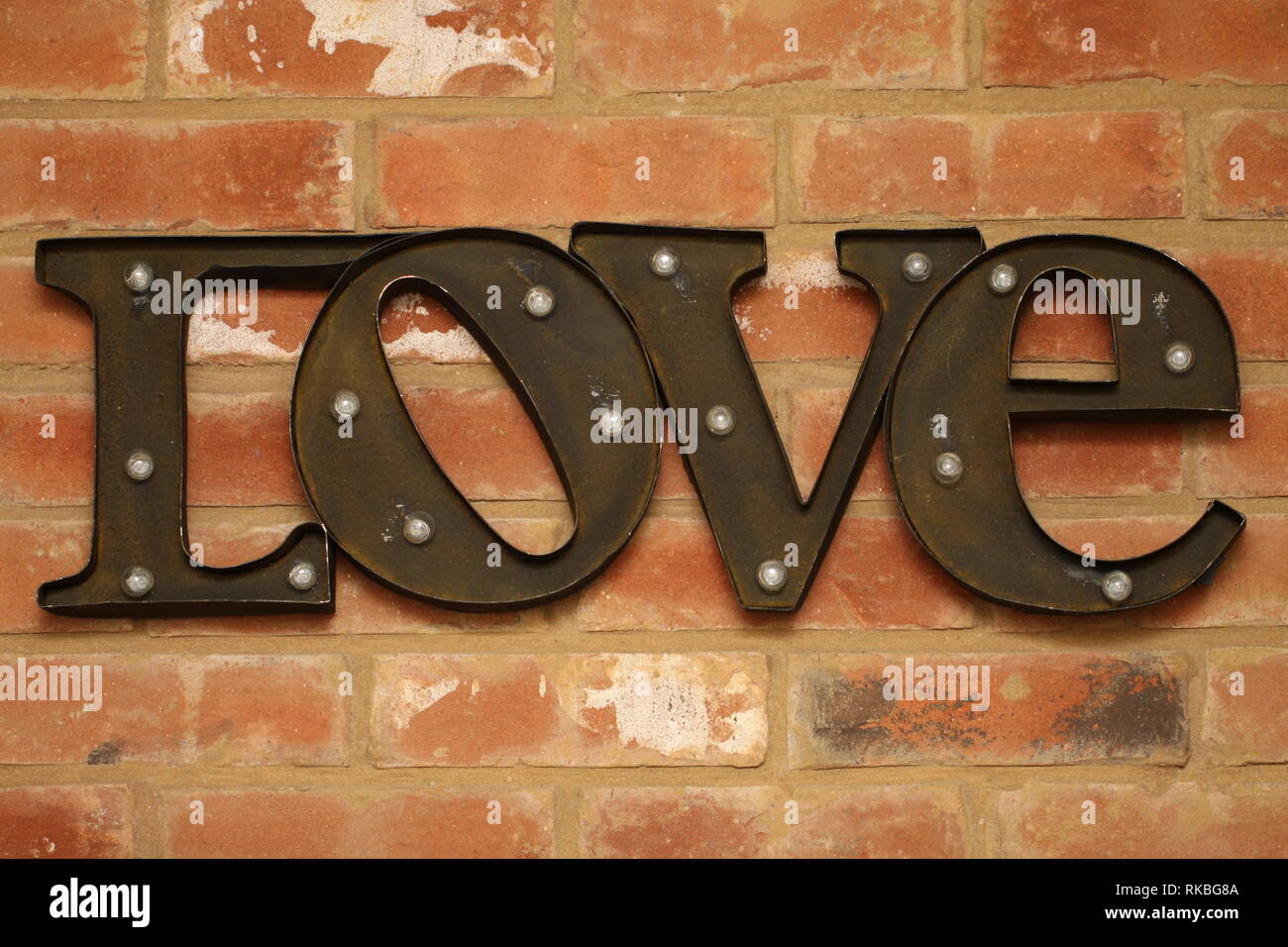 Brown metal Love sign mounted on red brick wall Stock Photo