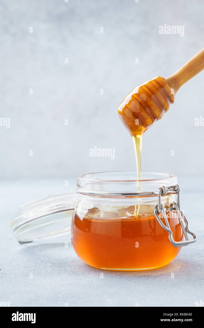 Honey dripping in a jar from wooden dipper. Stock Photo