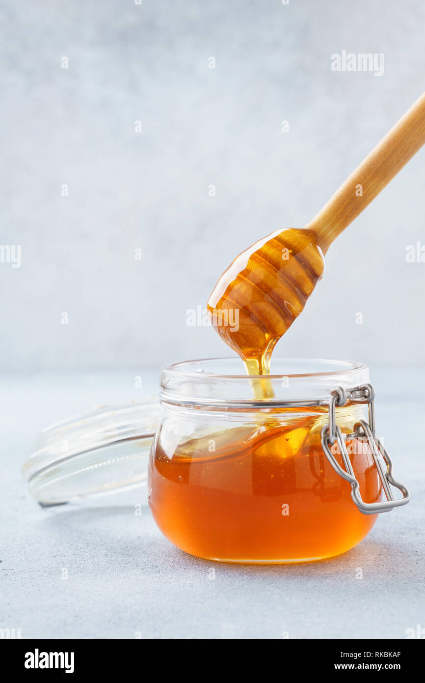 Honey dripping in a jar from wooden dipper. Stock Photo