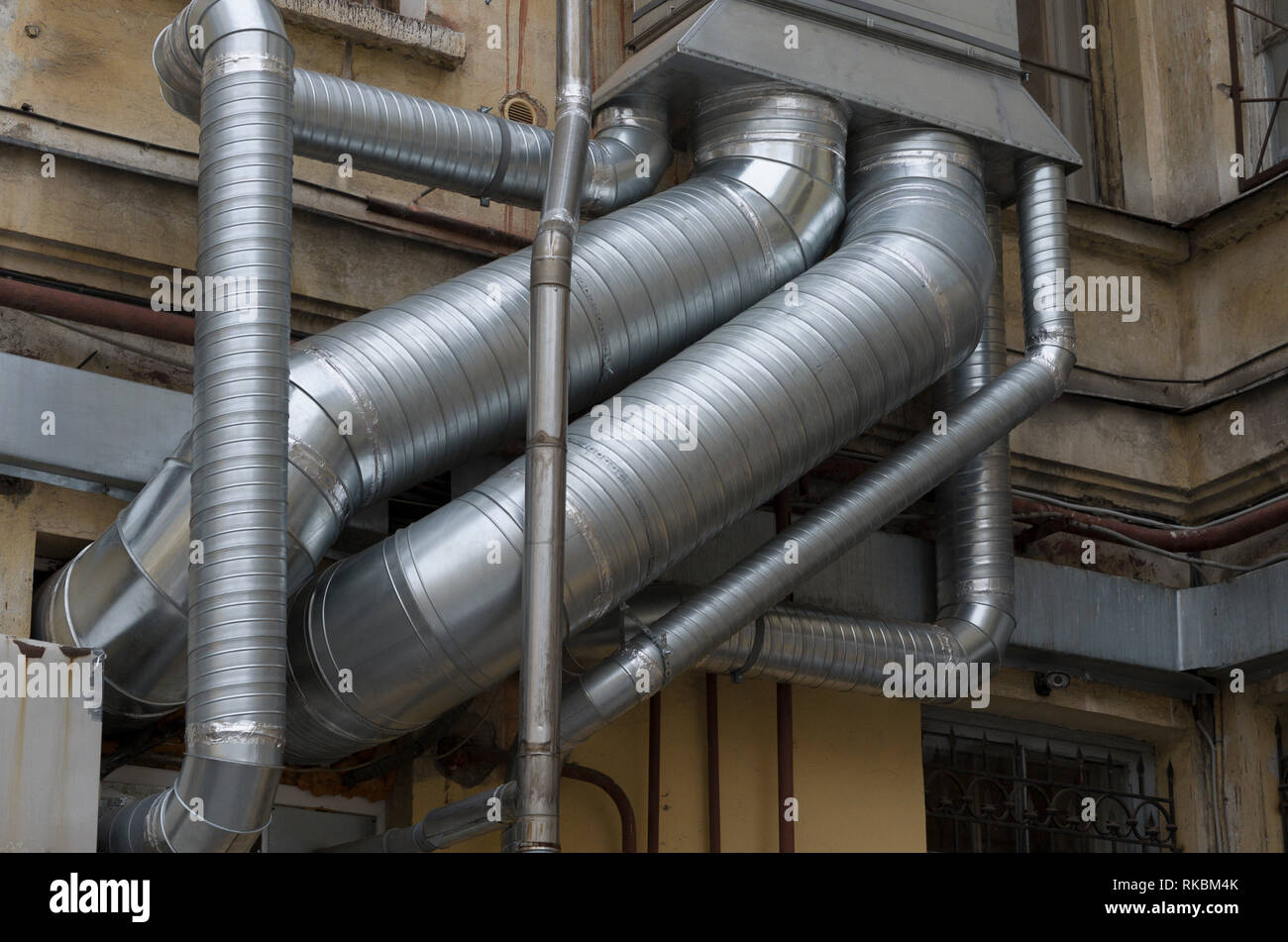 Interlacing of silver air ducts of different diameters on the old building closeup Stock Photo