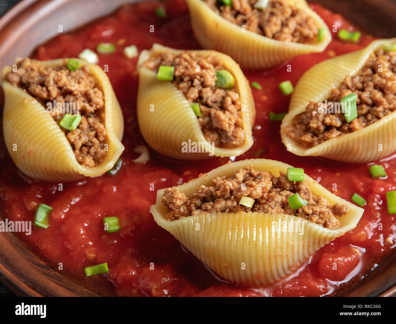 cooked pasta conchiglioni stuffed minced meat, tomato sauce close up Stock Photo