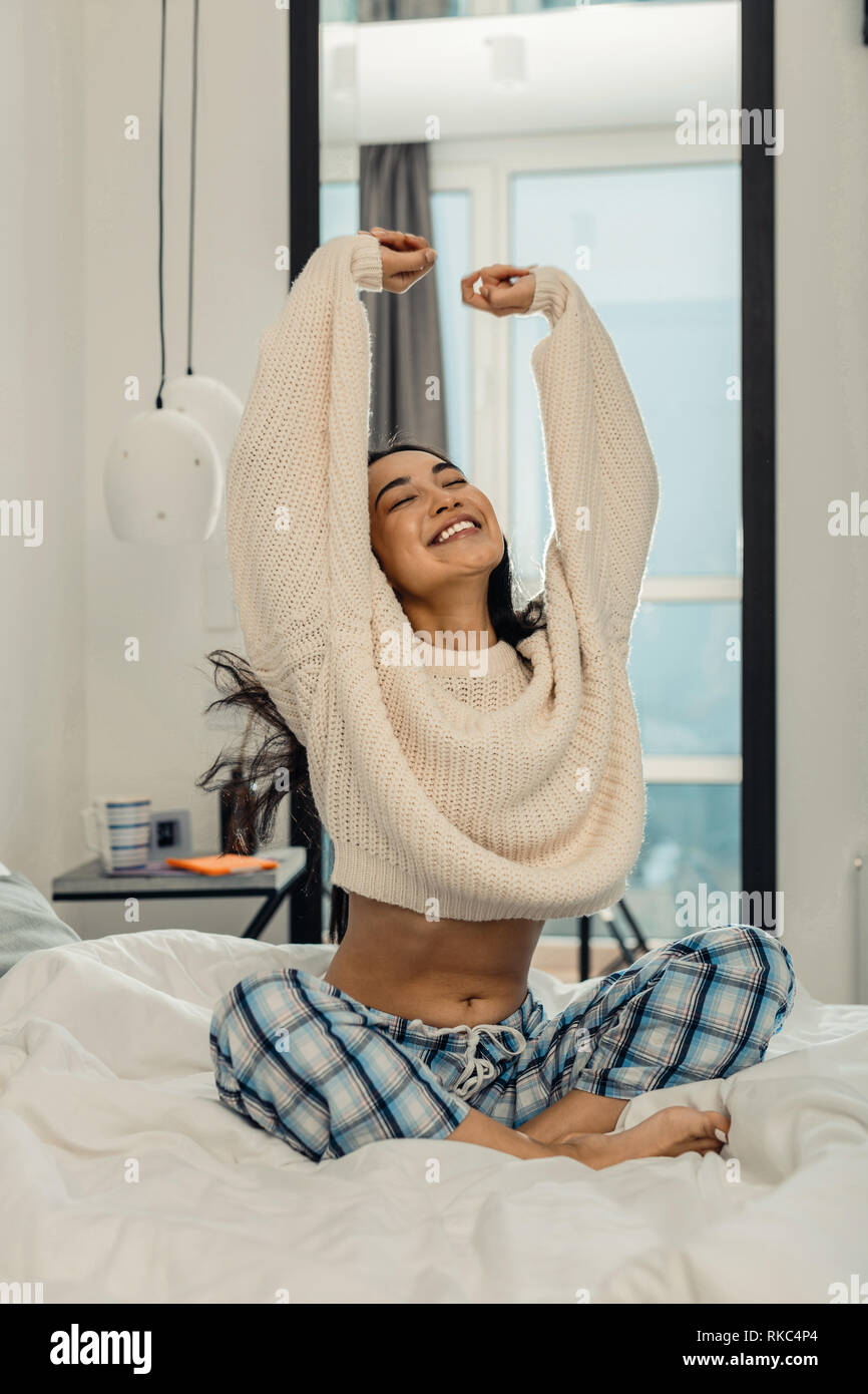 Woman wearing pajama trousers stretching and smiling Stock Photo