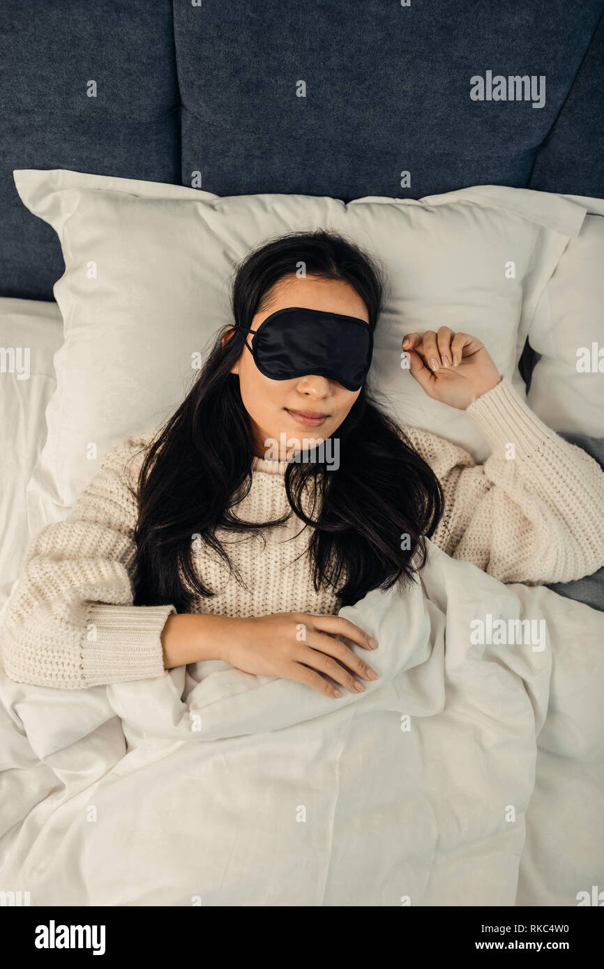 Asian woman wearing black sleeping mask lying in bed Stock Photo Alamy
