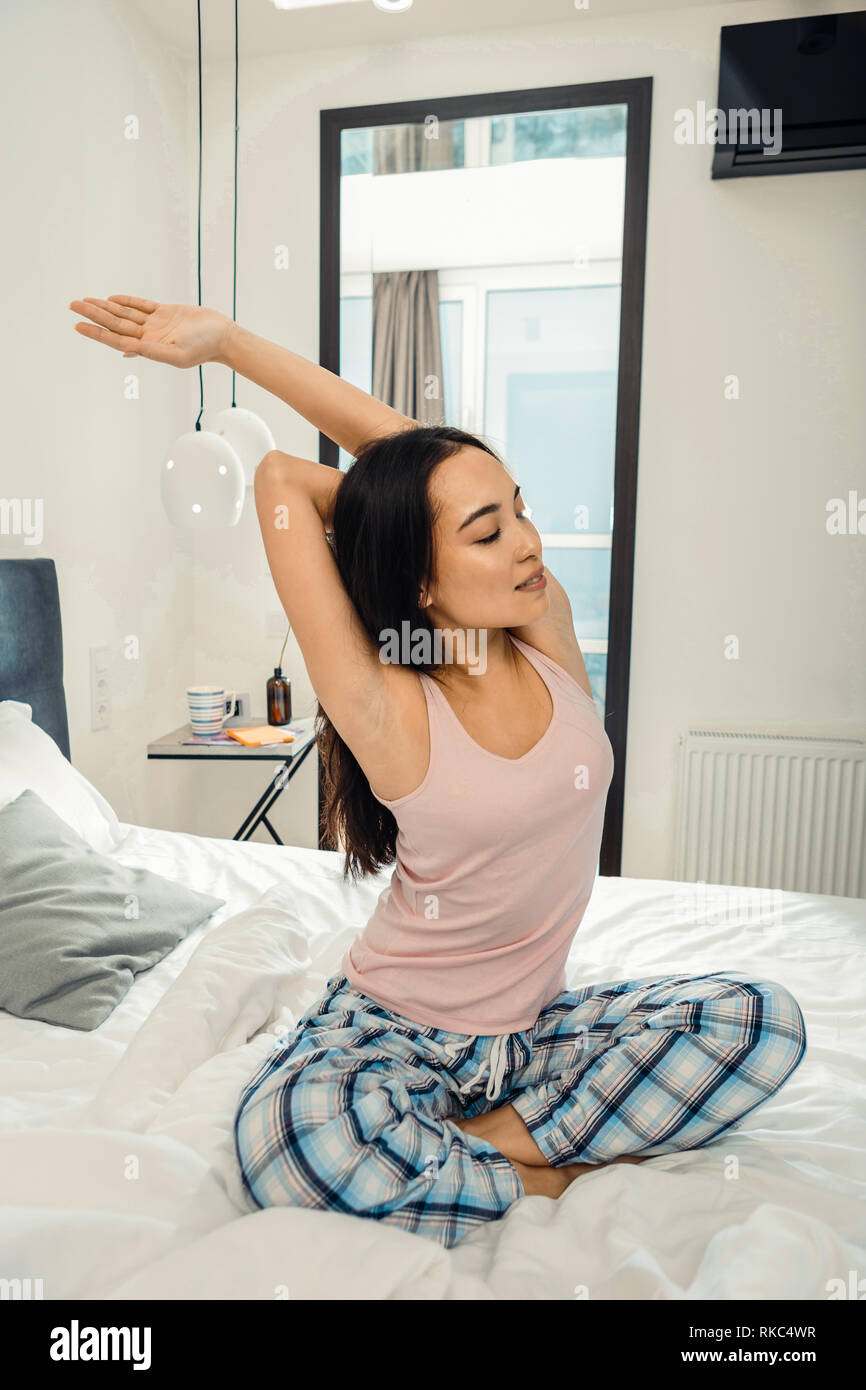 Slim woman wearing pajama trousers stretching in the morning Stock Photo