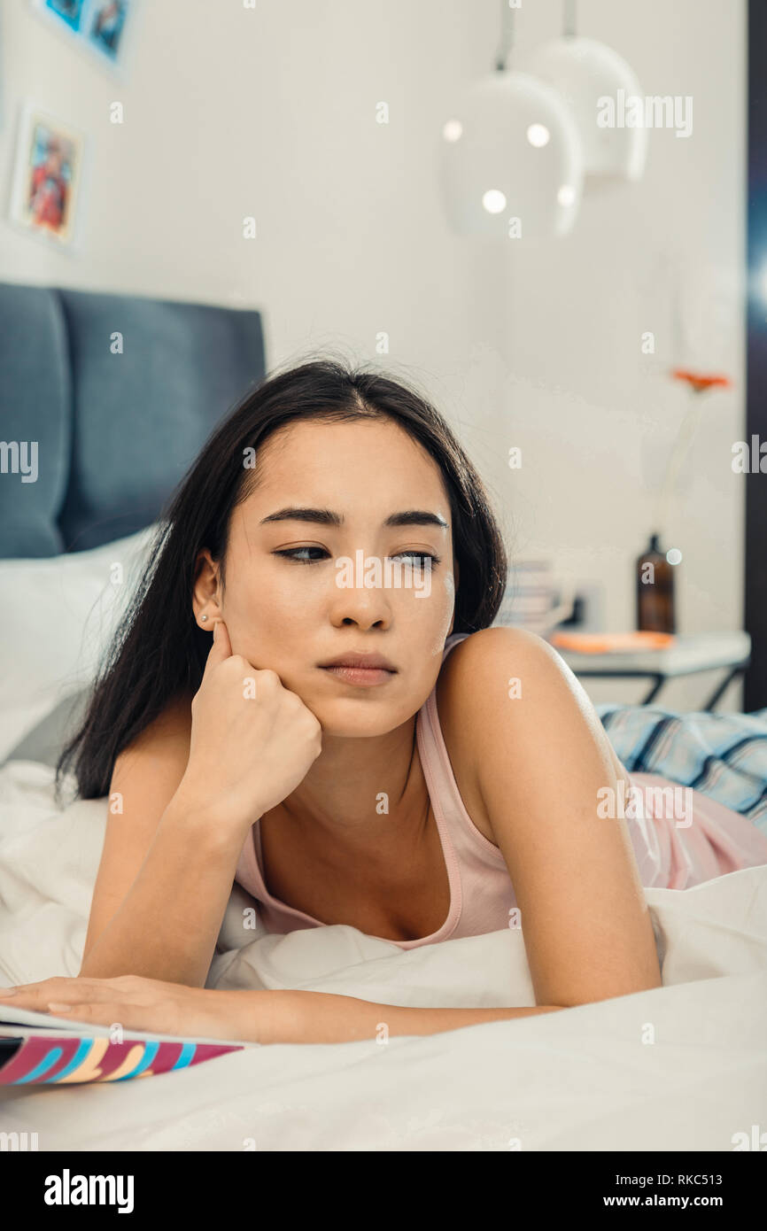 Dark-eyed woman feeling bored and lonely after reading book Stock Photo