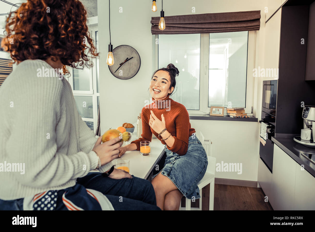 Roommates feeling involved in conversation in the kitchen Stock Photo