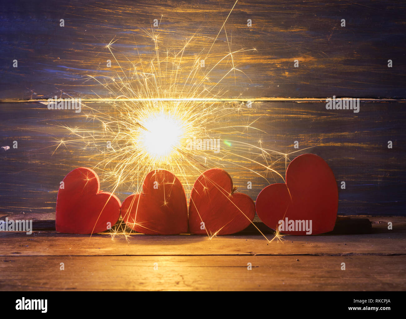 Bengal lit with four red hearts on a wooden board. Long exposition Stock Photo