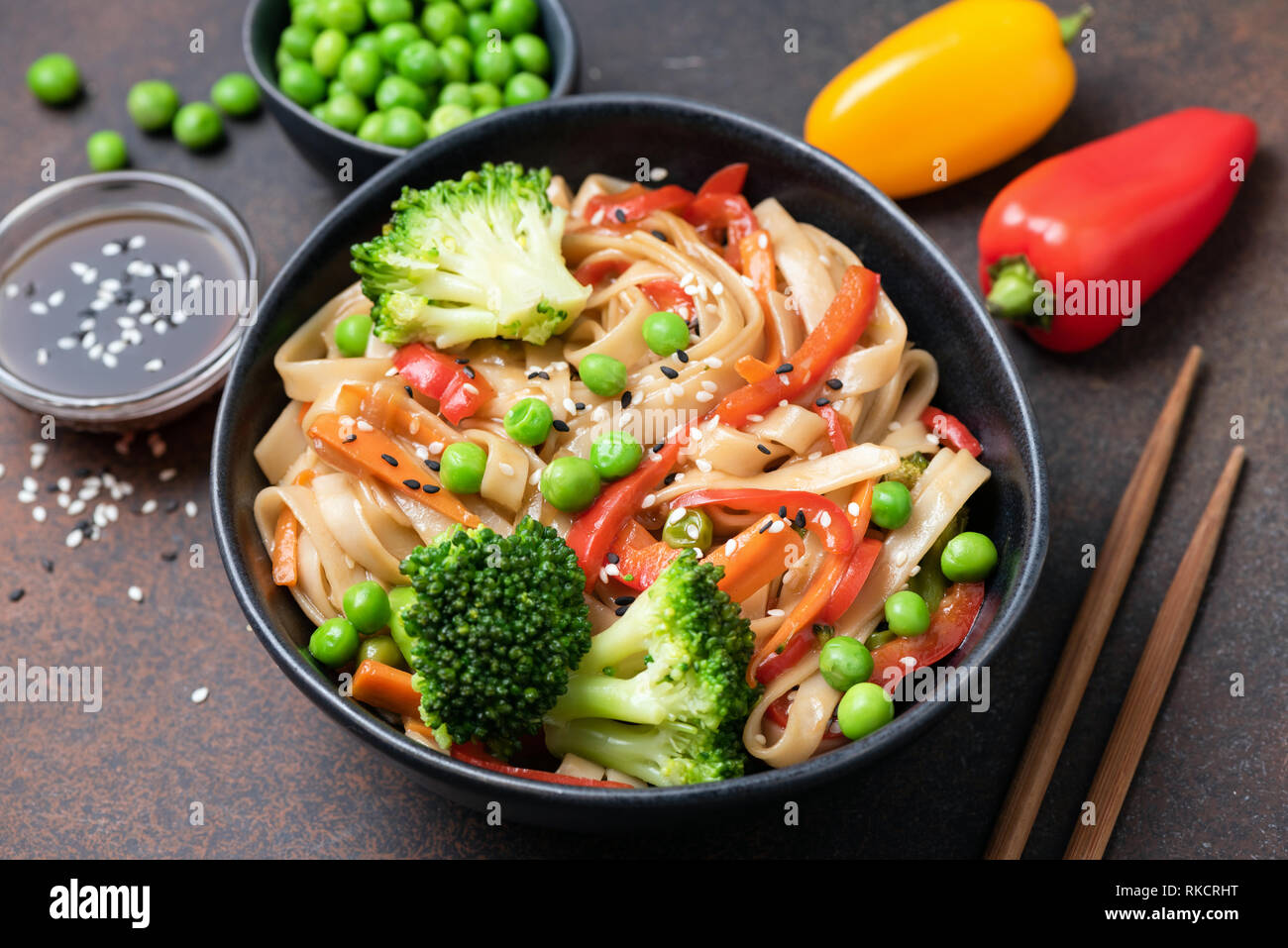 Asian noodle stir fry with vegetables in bowl. Udon noodles with broccoli, pepper, carrot and green peas Stock Photo