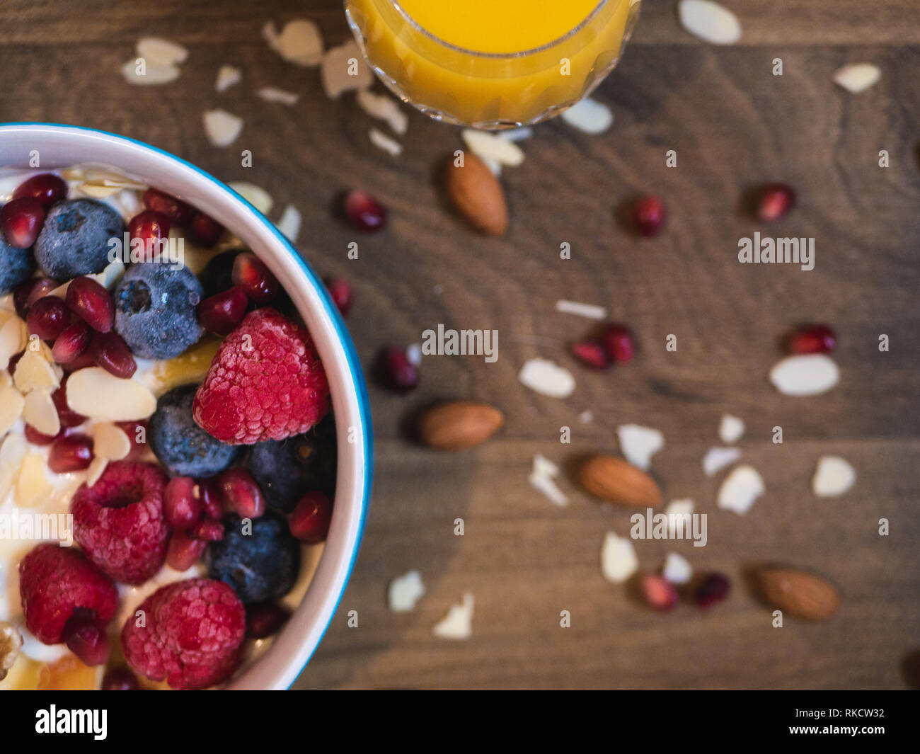Delicious and healthy breakfast bowl with raspberry, blueberry, almond, pomegranate, walnuts and soy yogurt Stock Photo