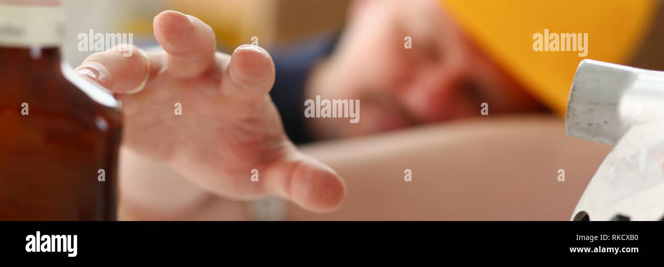 Arm of drunken worker in yellow helmet Stock Photo