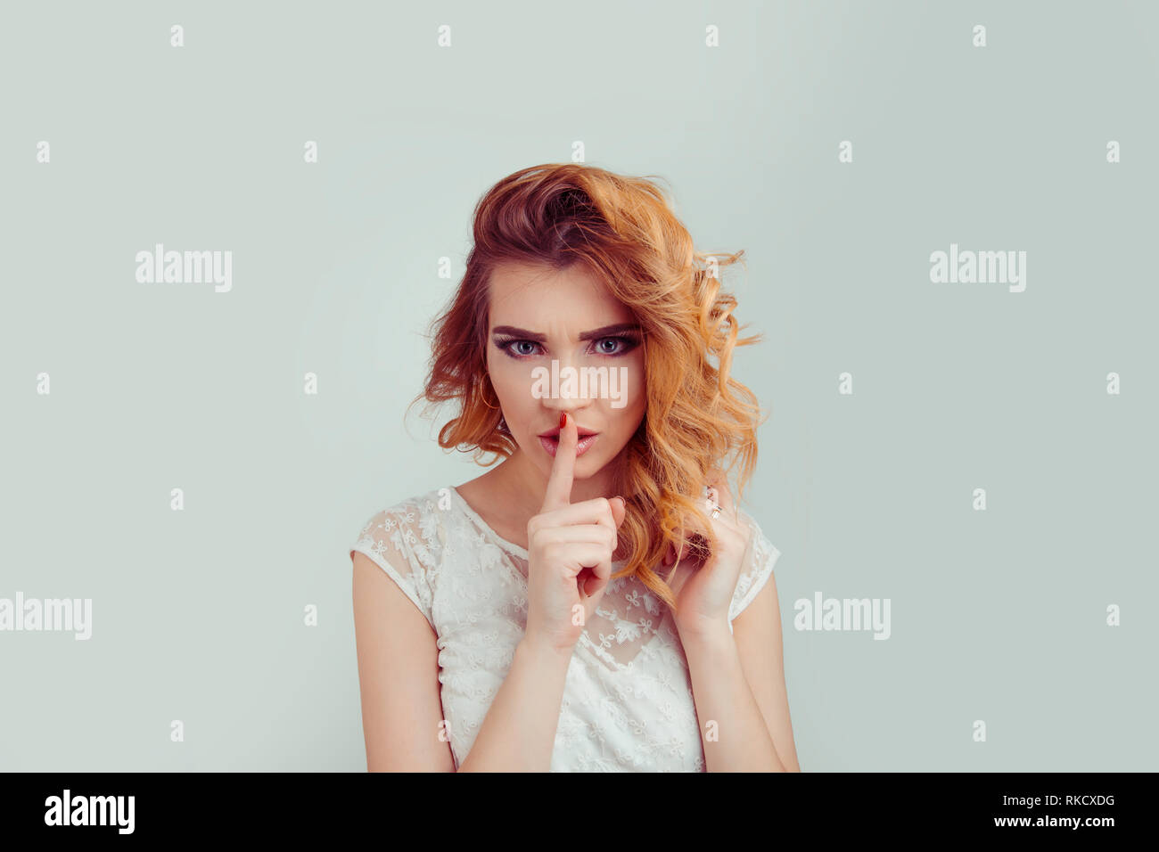 Woman asking for silence or secrecy with finger on lips hush hand gesture Stock Photo