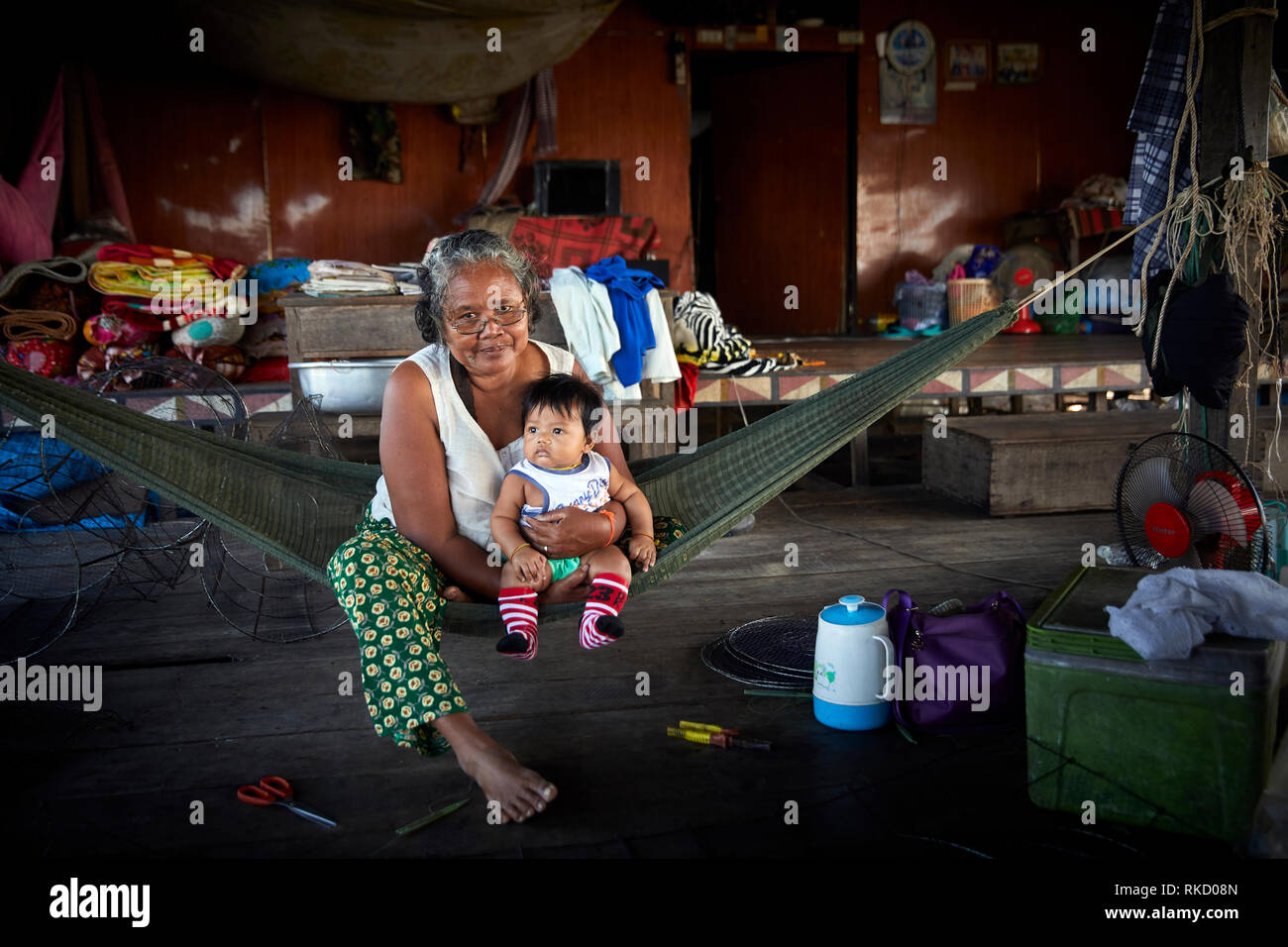 Tonlé Sap Lake, Cambodia. 17th December, 2018. Grandmother holds her  grandchild while sitting in a hammock inside their floating home. Photo:  Bryan Stock Photo - Alamy