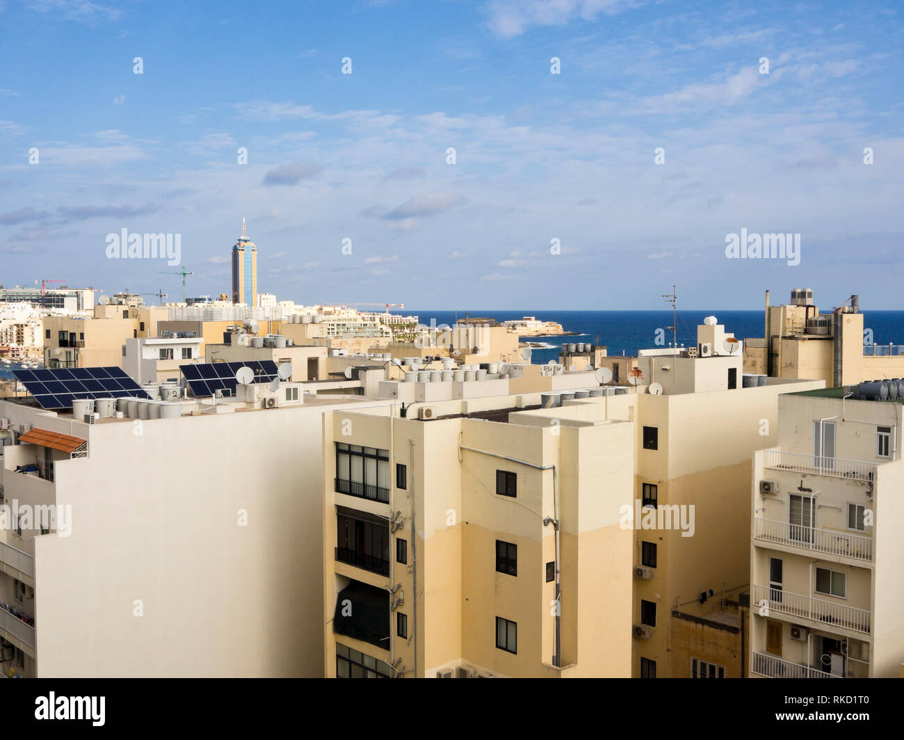 Looking out over the rooftops in the densely built up and populated Saint Julians in Malta, onto the blue Mediterranean sea with the Casino inn the mi Stock Photo