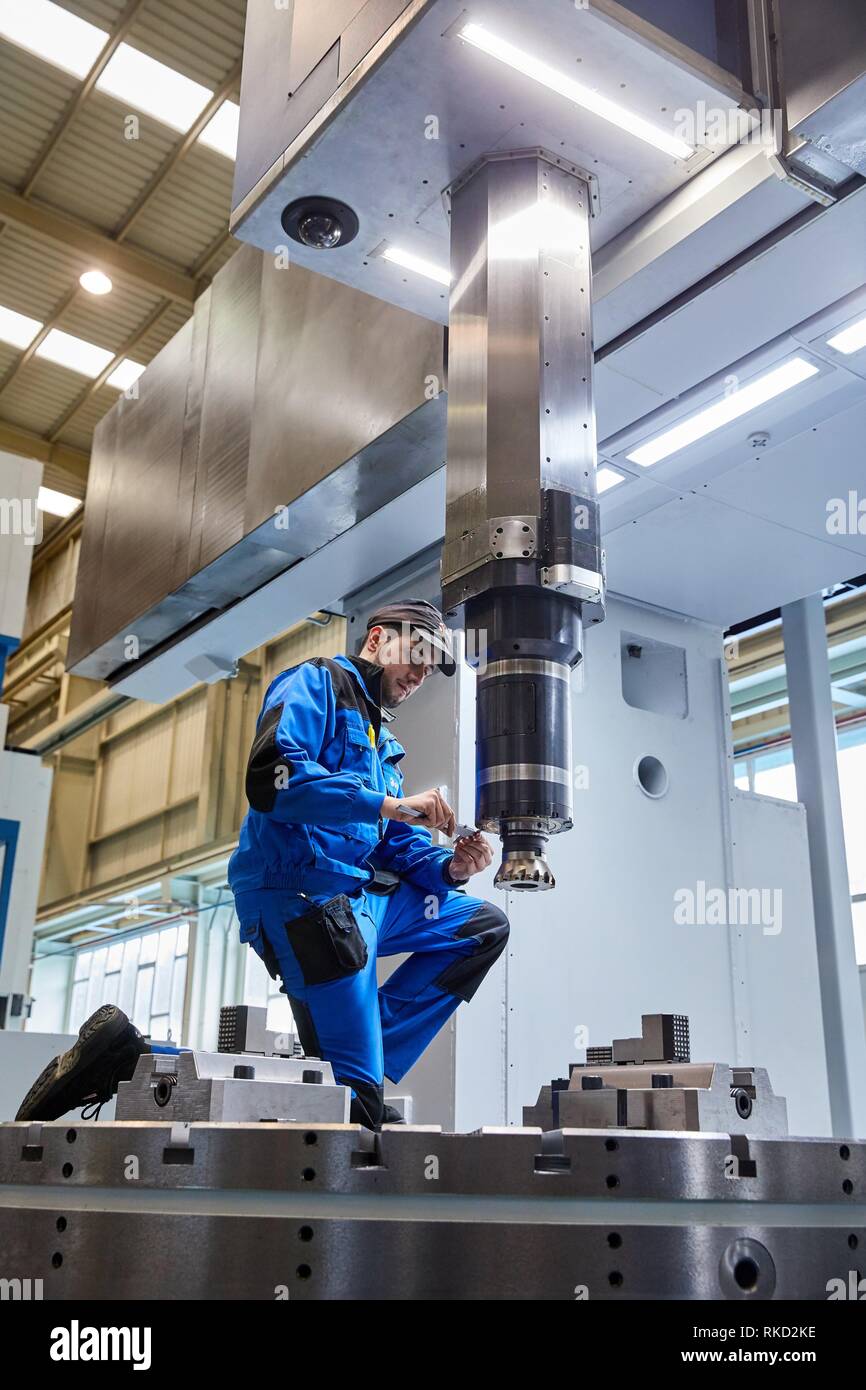 Technician adjusting lathe head with cutting tool, Vertical lathe