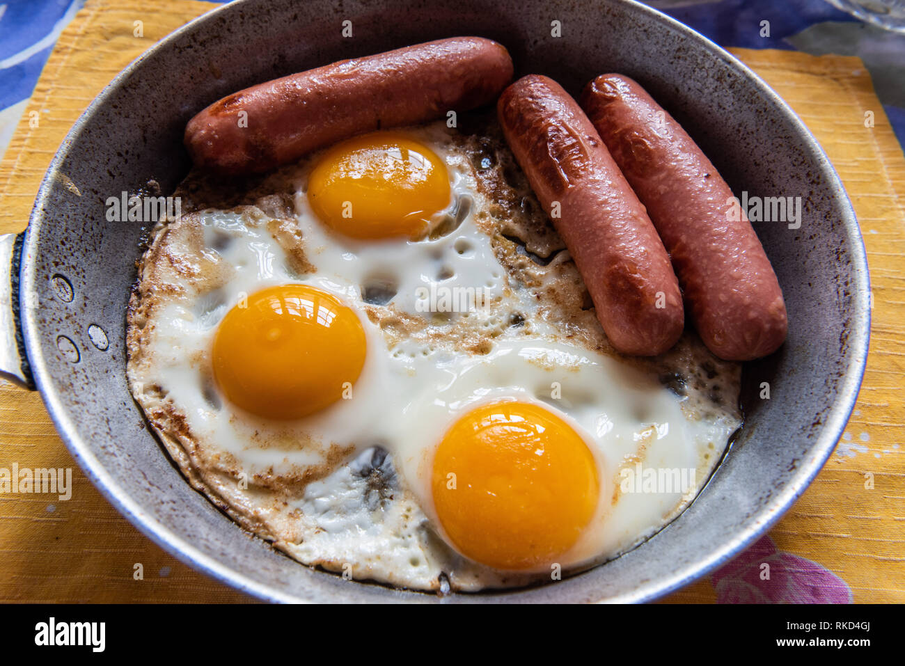 Breakfast meal of three sausages and fried eggs. Stock Photo