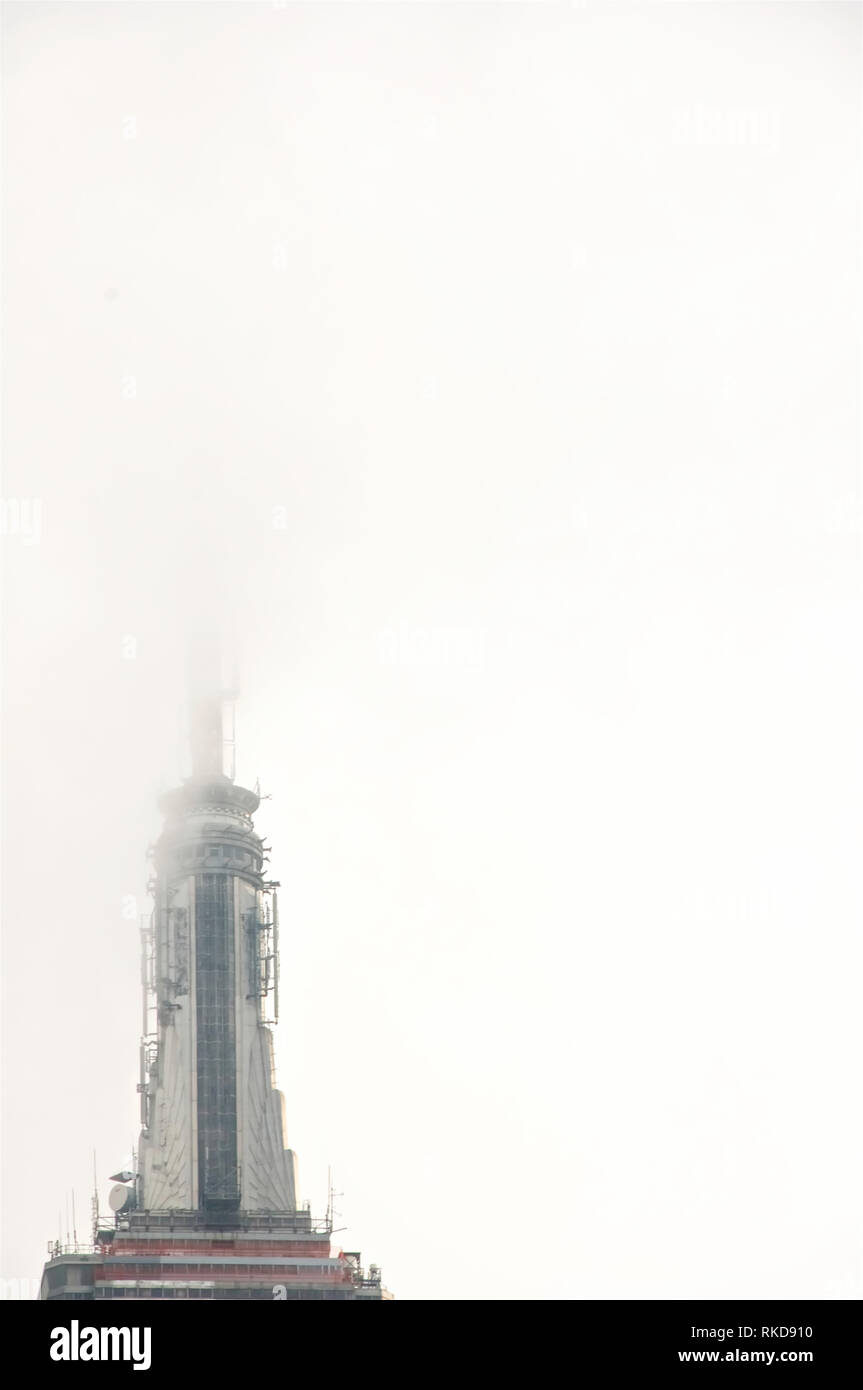 A cloud and mist obscured and covered tip of the iconic and symbolic Empire State Building in New York City's Manhattan. Stock Photo