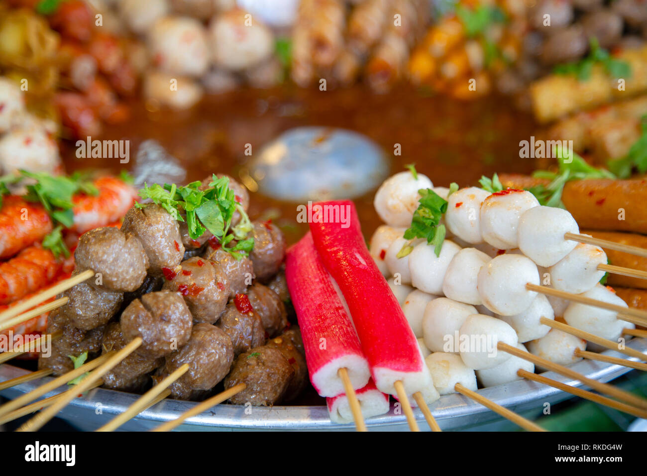 An arrangement of skewered cooked meat and seafood street food snacks and appetizers in a market stall in Phuket, Thailand. Stock Photo