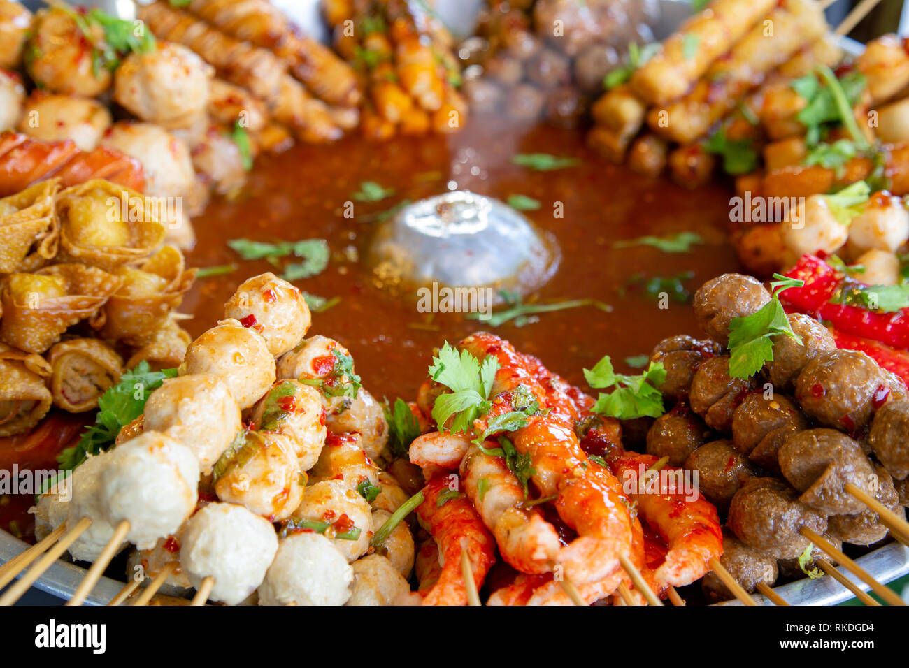 An arrangement of skewered cooked meat and seafood street food snacks and appetizers in a market stall in Phuket, Thailand. Stock Photo