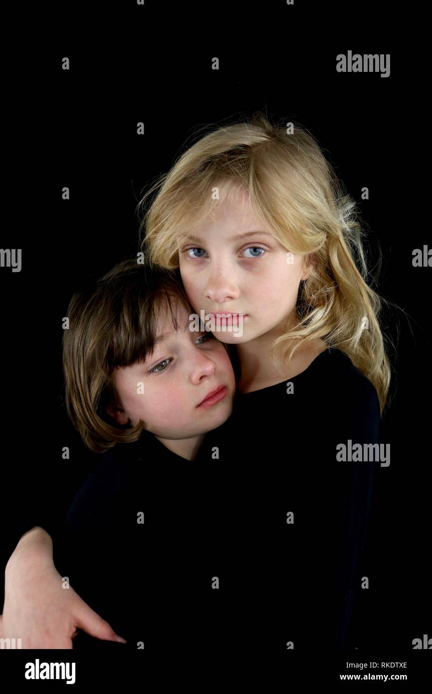 Two young sisters grieving and holding each other Stock Photo