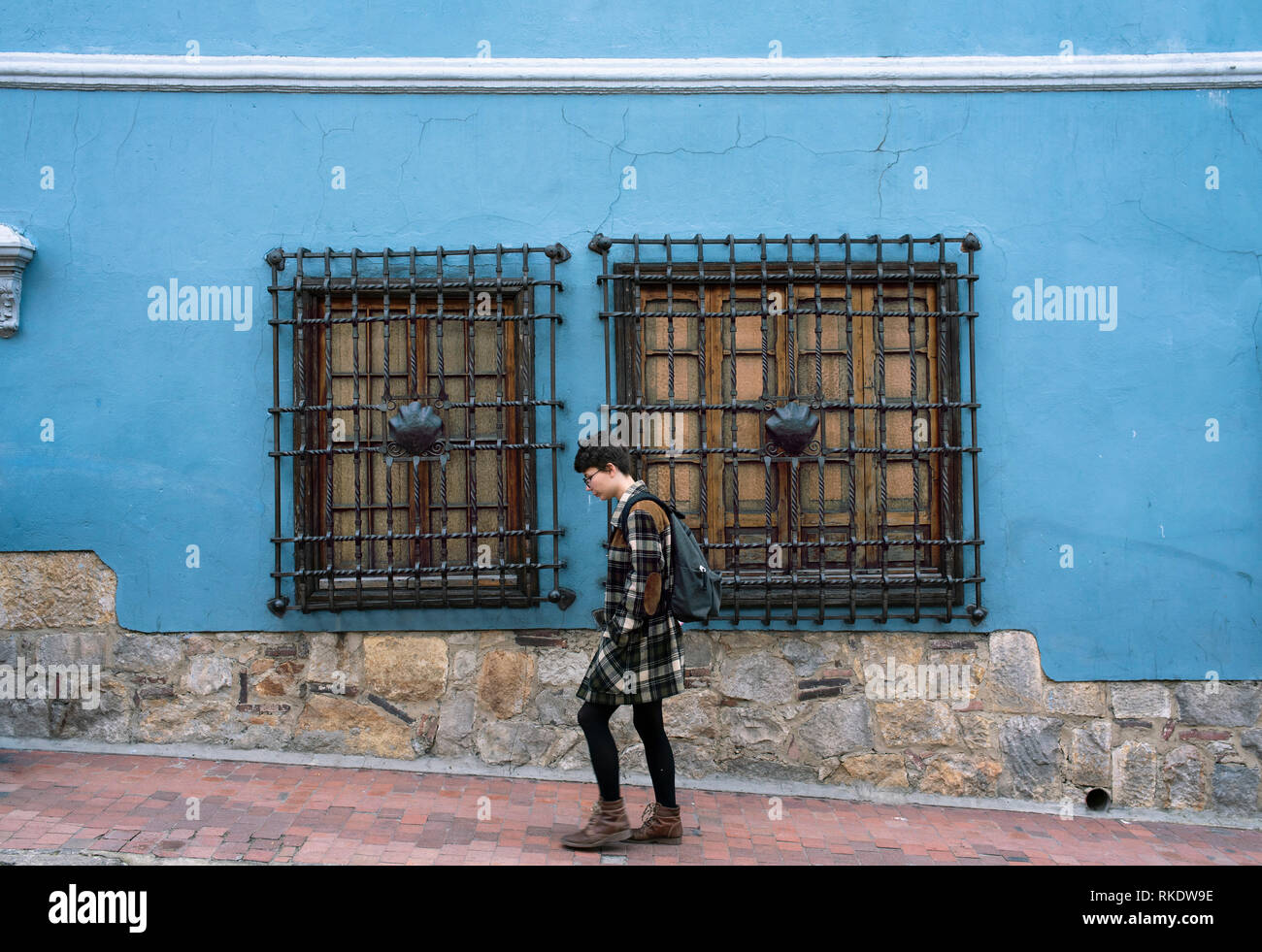 Student walking on the street of La Candelaria, historic district of Bogotá, Colombia. Rustic architectural details with matching colours. Sep 2018 Stock Photo