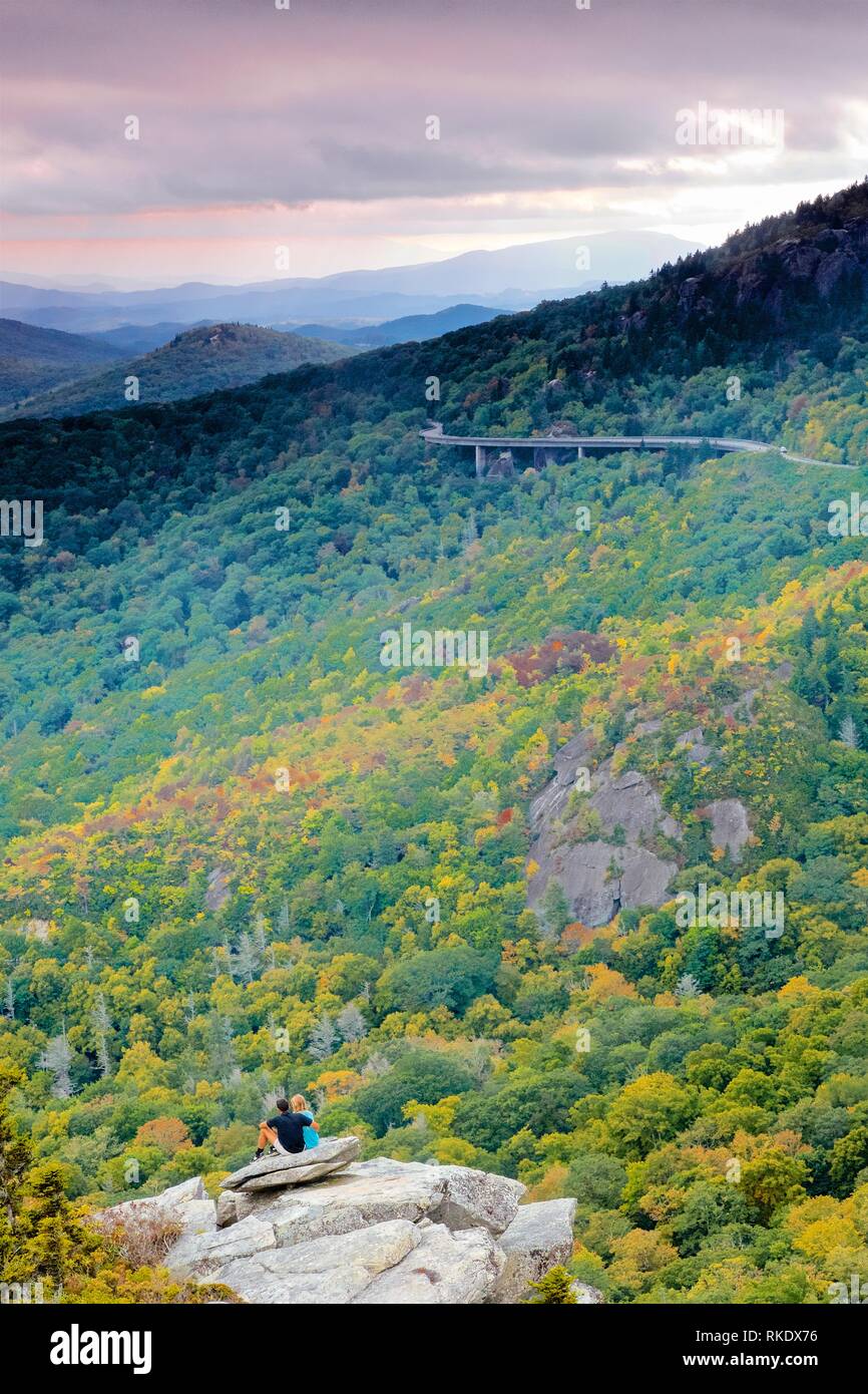 A Couple Enjoy the View of the Linn Cove Viaduct From Mountaintop in Autumn Scene Stock Photo