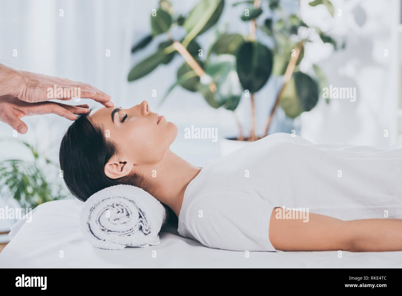 side view of calm young woman with closed eyes receiving reiki ...