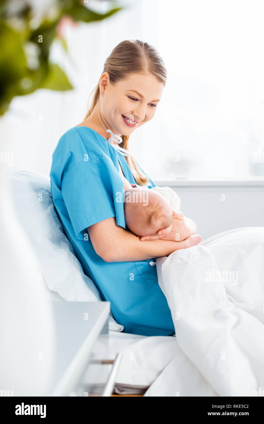 side view of beautiful happy young mother breastfeeding newborn baby on