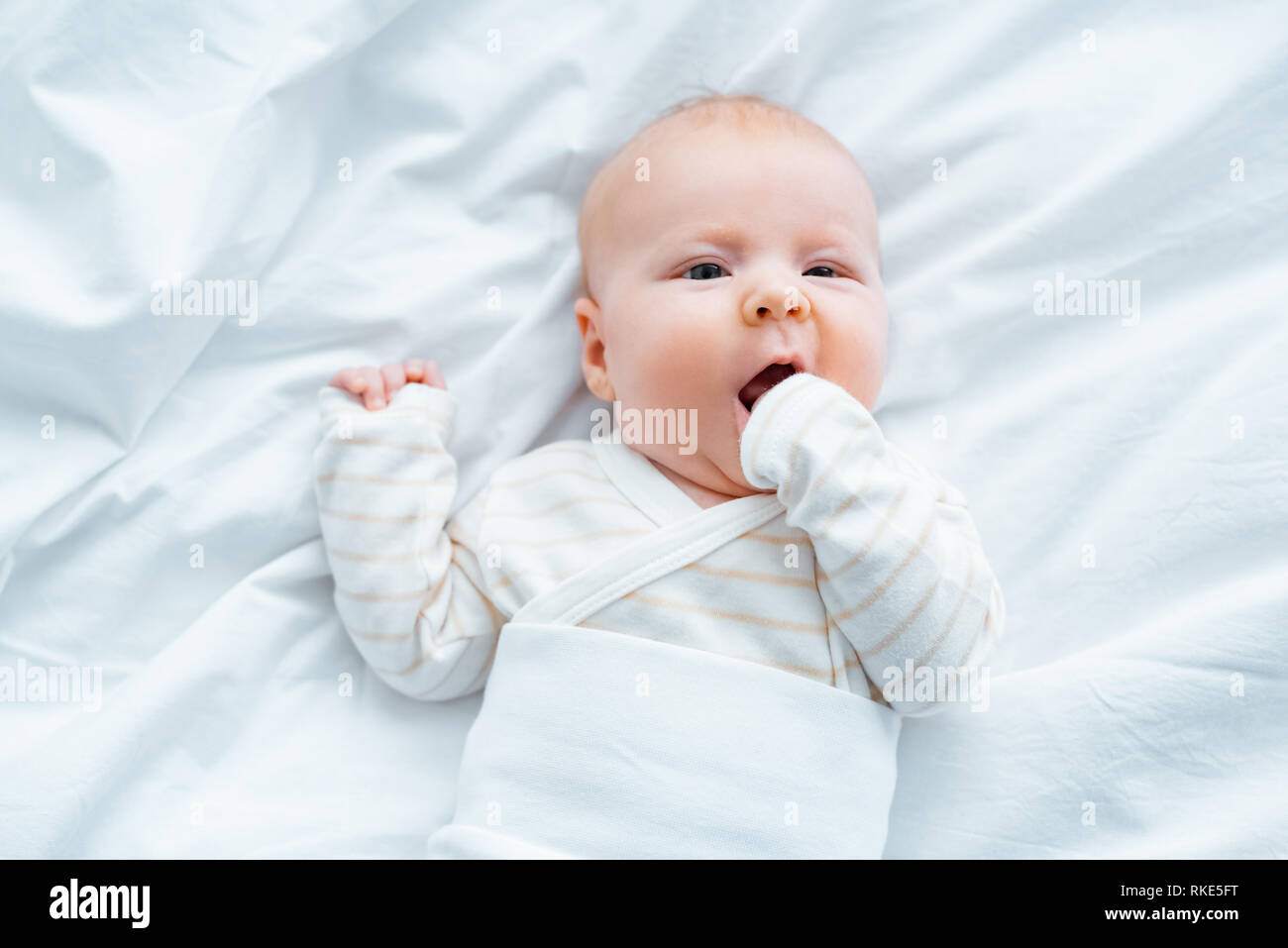 top view of adorable baby lying on white bedding Stock Photo