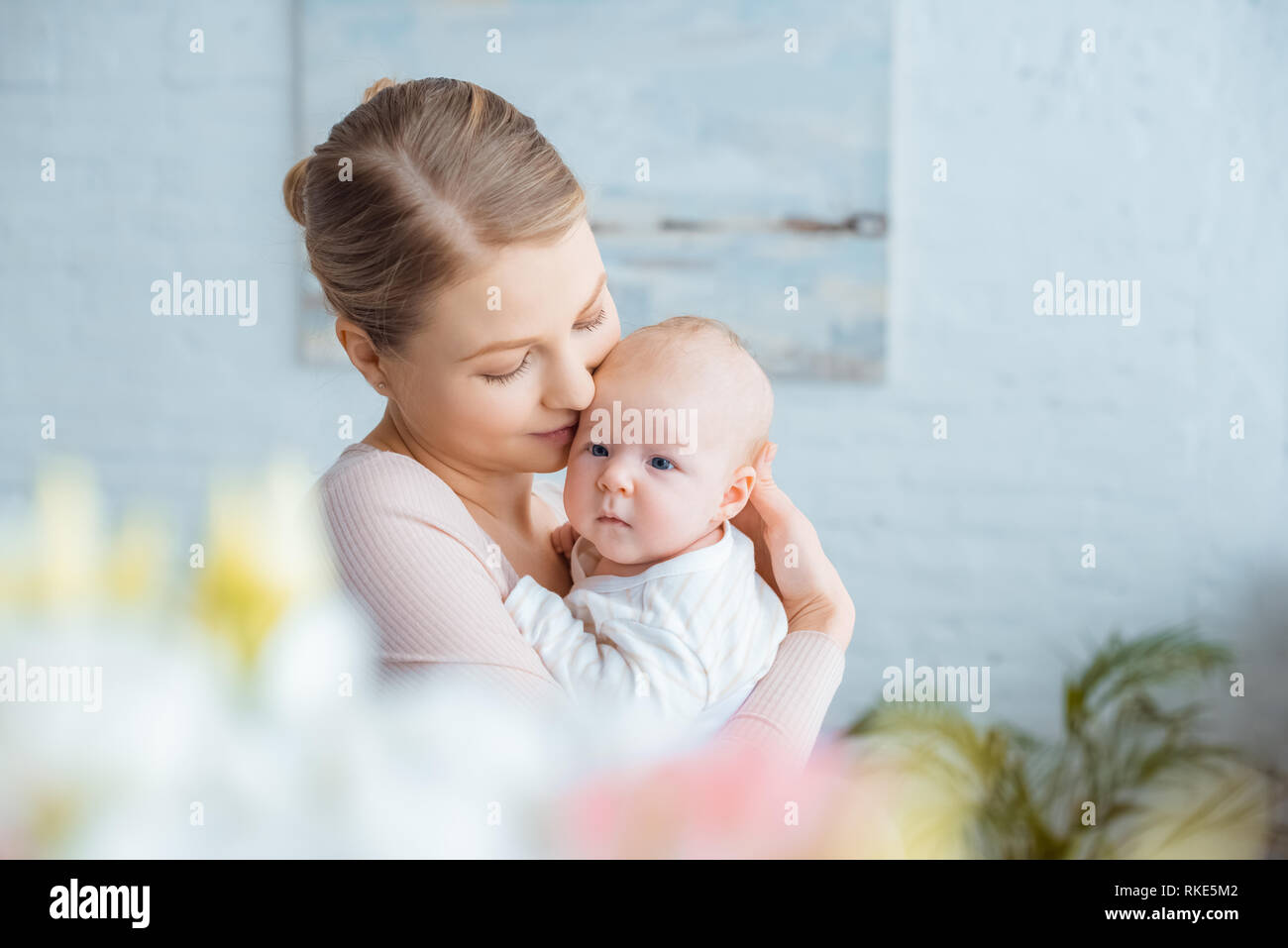 selective focus of happy young mother hugging adorable baby at home Stock Photo