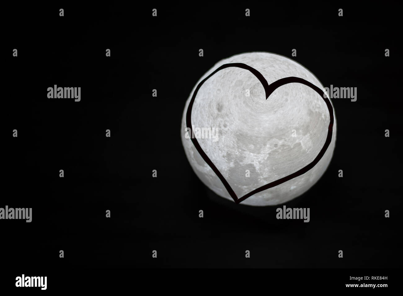 Black and white photo of small moon light with heart countor shape in front Stock Photo