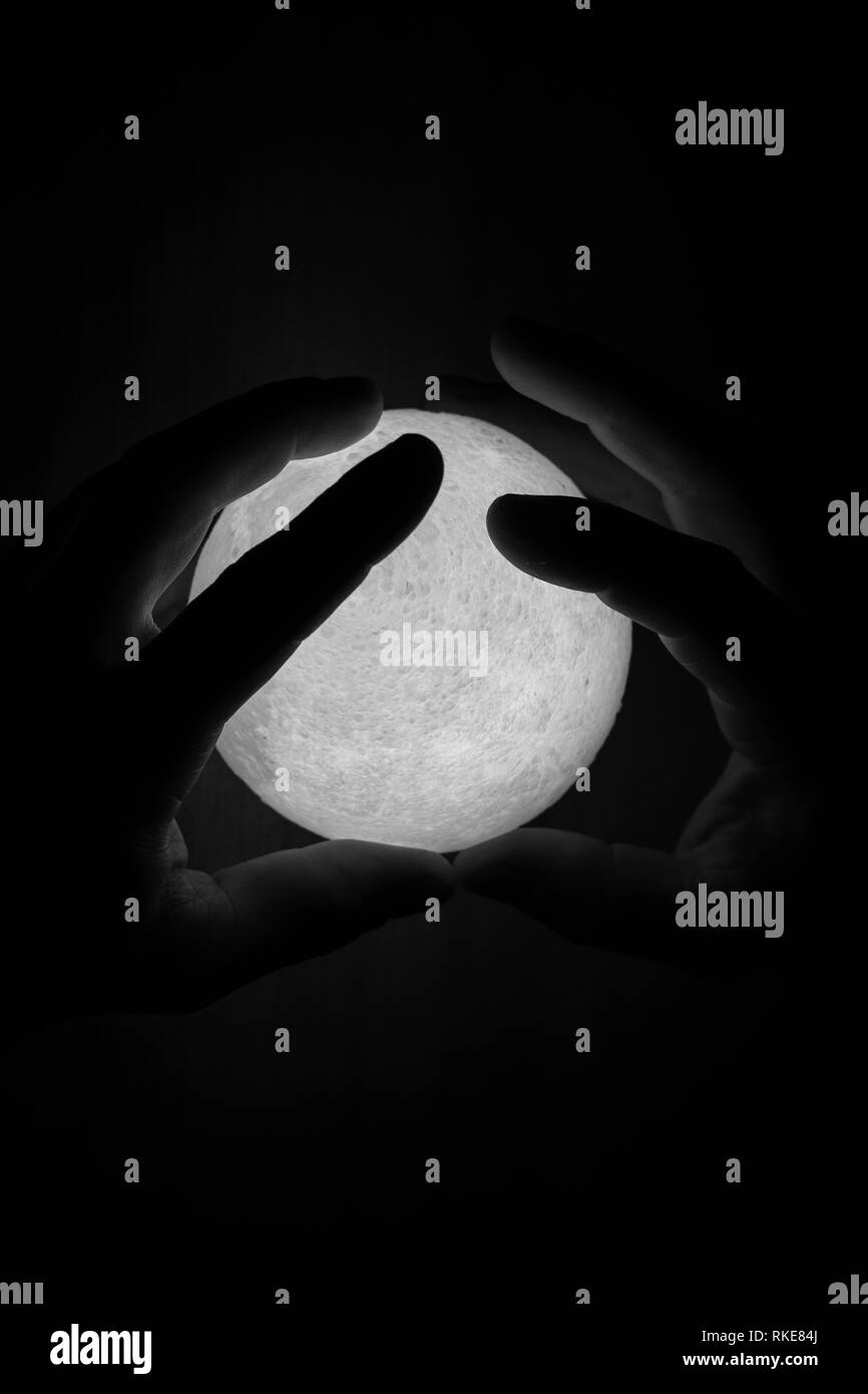 Black and white image of small moon light in mans hands. Abstract photo Stock Photo