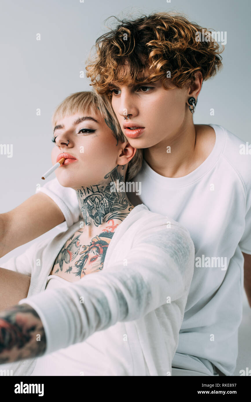Blonde Tattooed Girl Holding Cigarette In Mouth Near