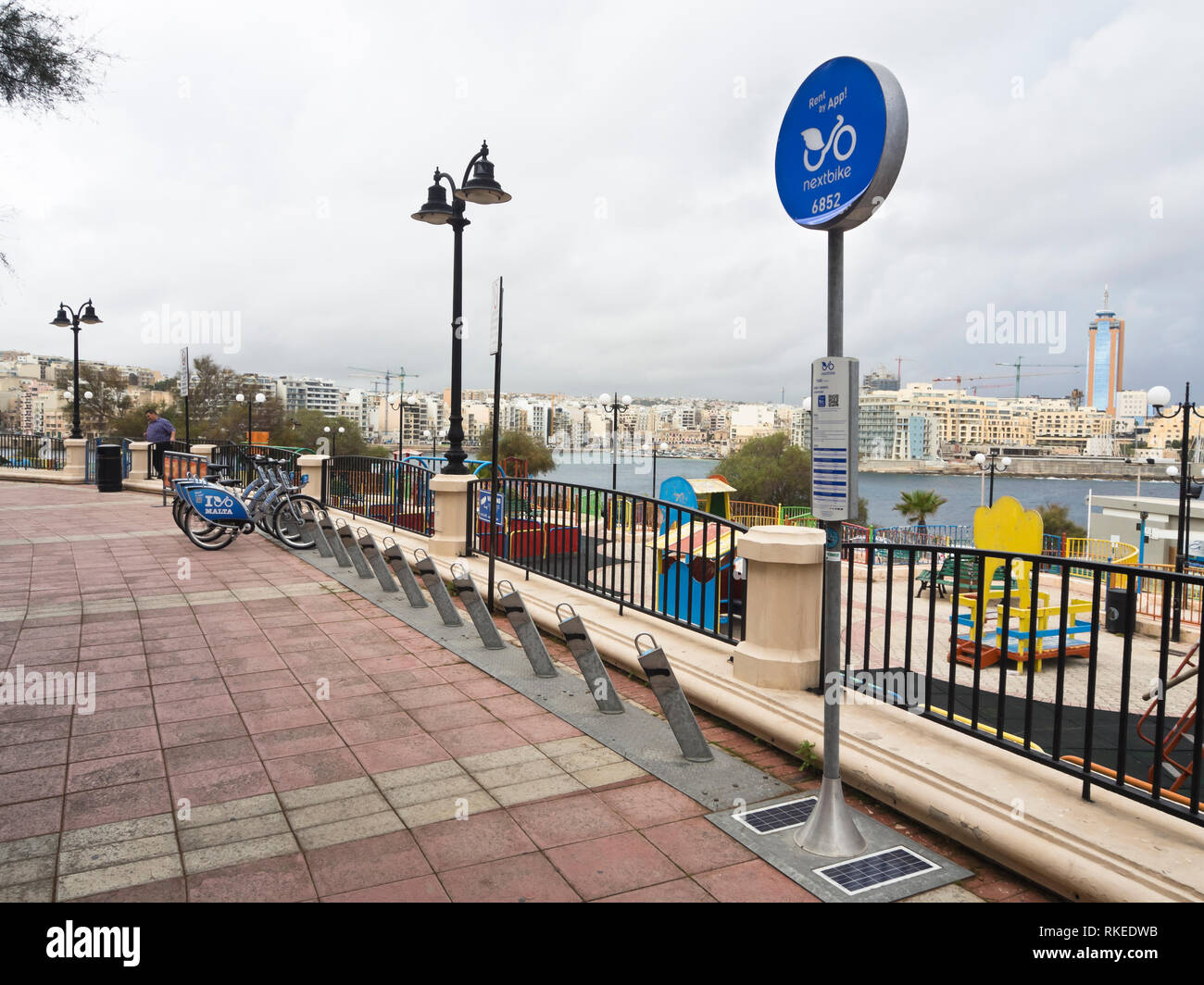 Seaside promenade in Sliema Malta with parking space for rental bikes and a children's playground Stock Photo