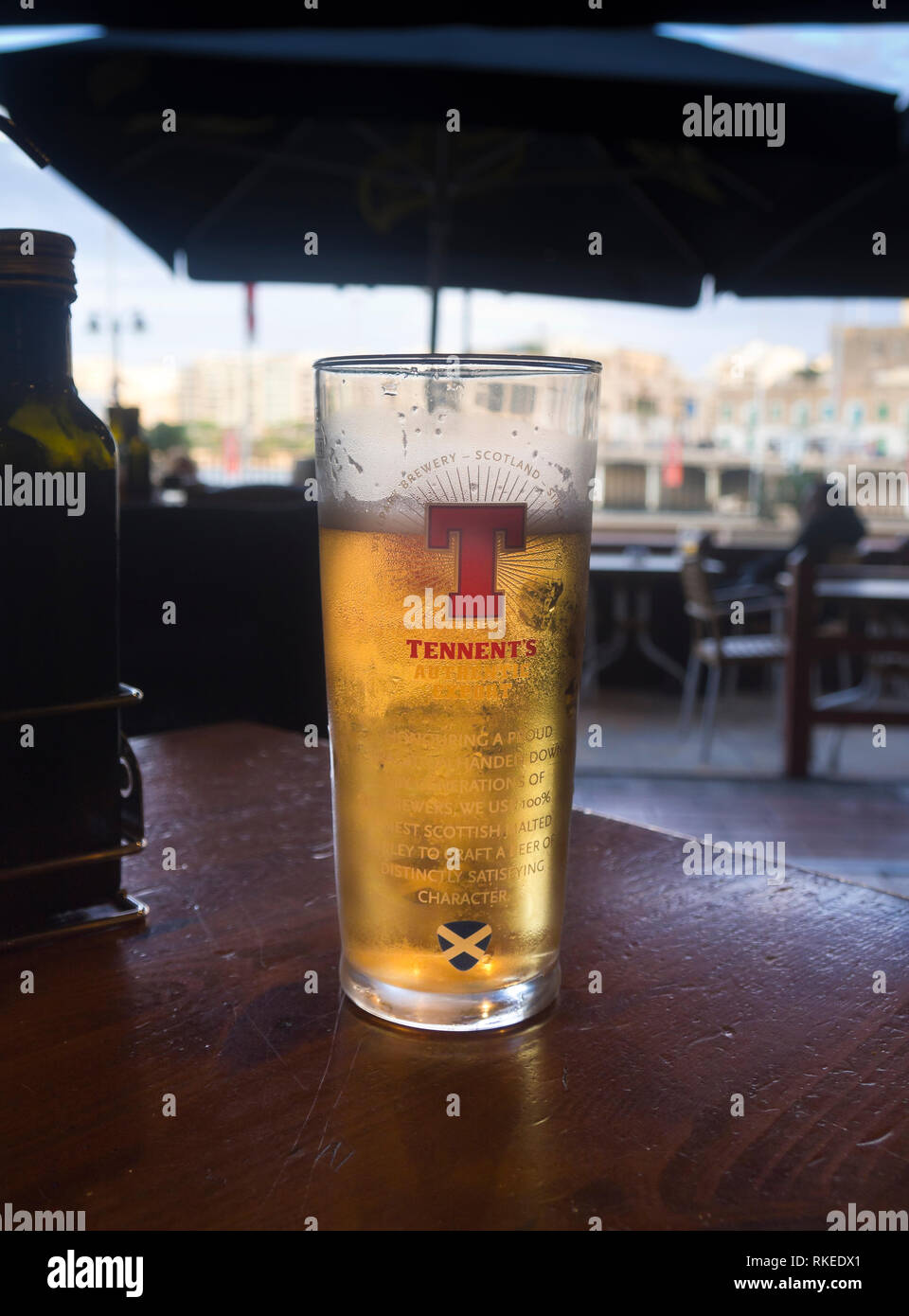 A glass of Tennent beer, relaxing in the shade on the seafront promenade near Valetta Malta Stock Photo