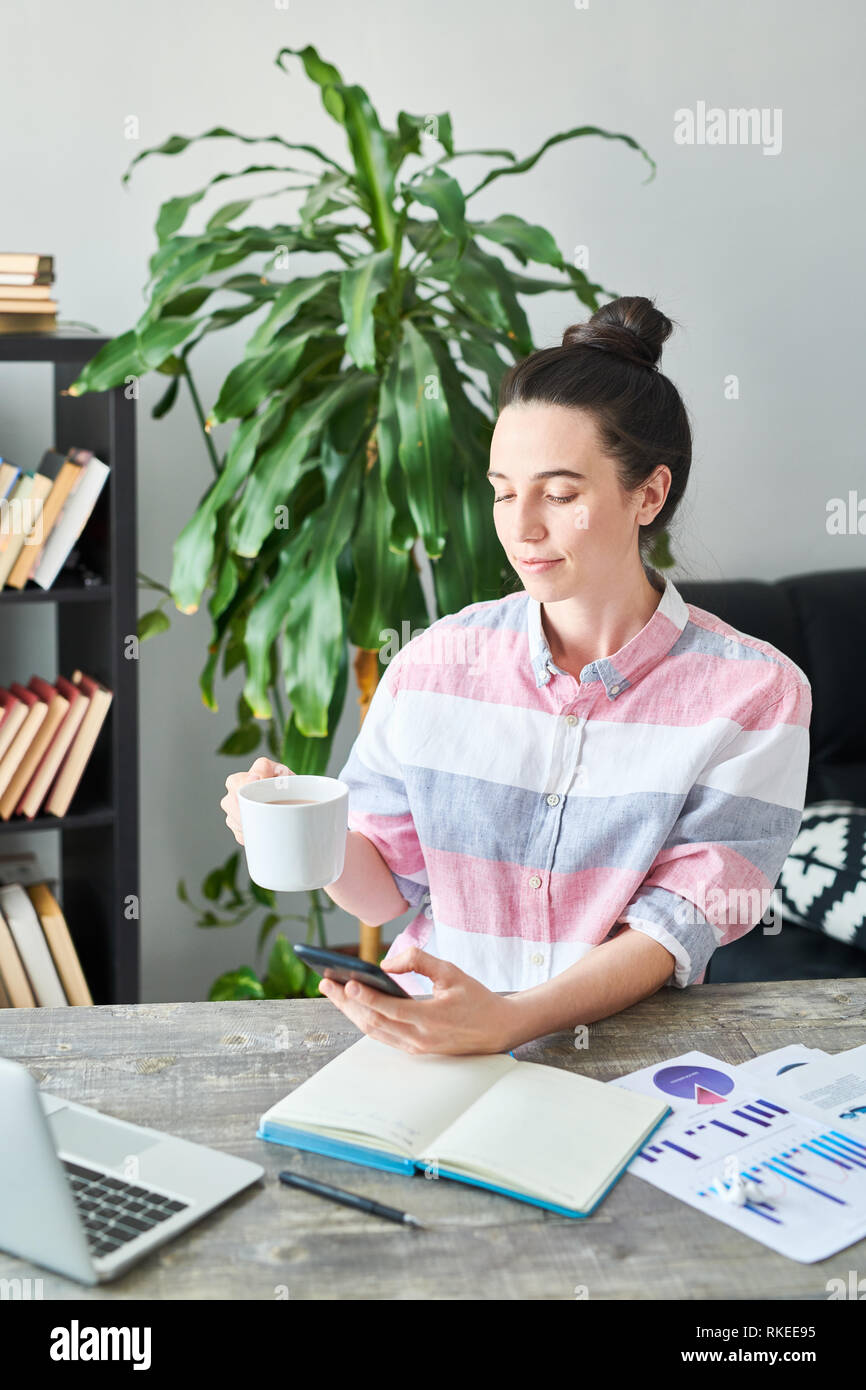 Woman using Smartphone at Workplace Stock Photo