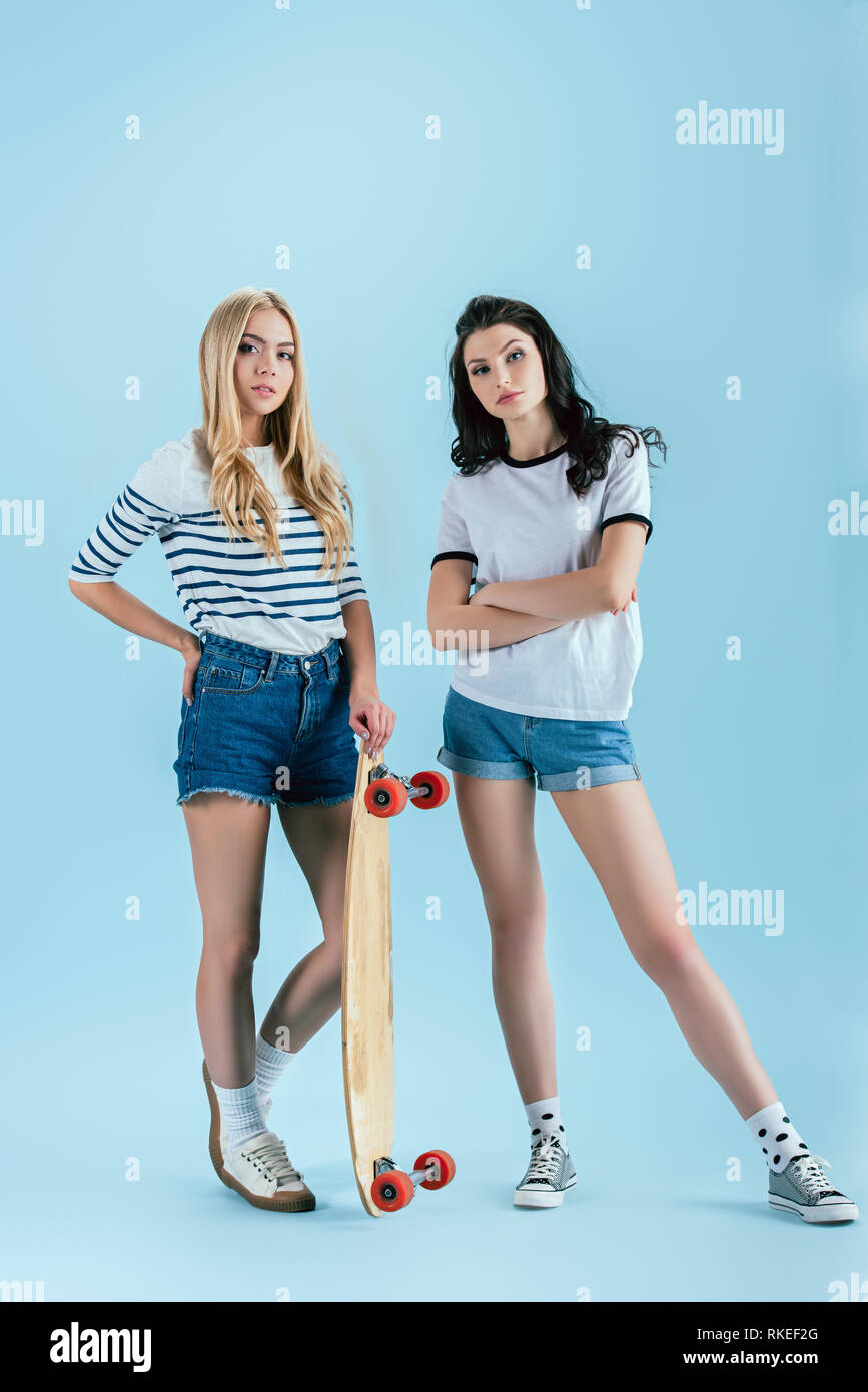 Winsome girls posing with longboard on blue background Stock Photo