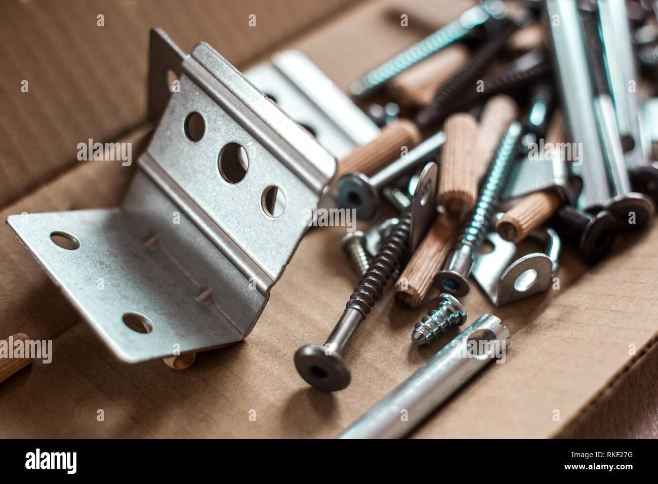 Furniture fittings, screws and other parts in open craft box lying on the floor, furniture assembly at home Stock Photo
