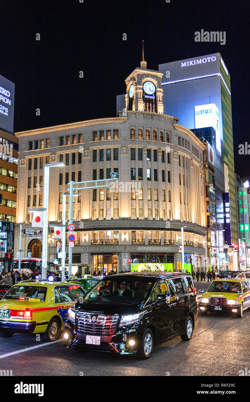 Tokyo, Ginza, night. 4-chome intersection with traffic and taxis passing by, with the landmark corner Wako Department store illuminated. Stock Photo