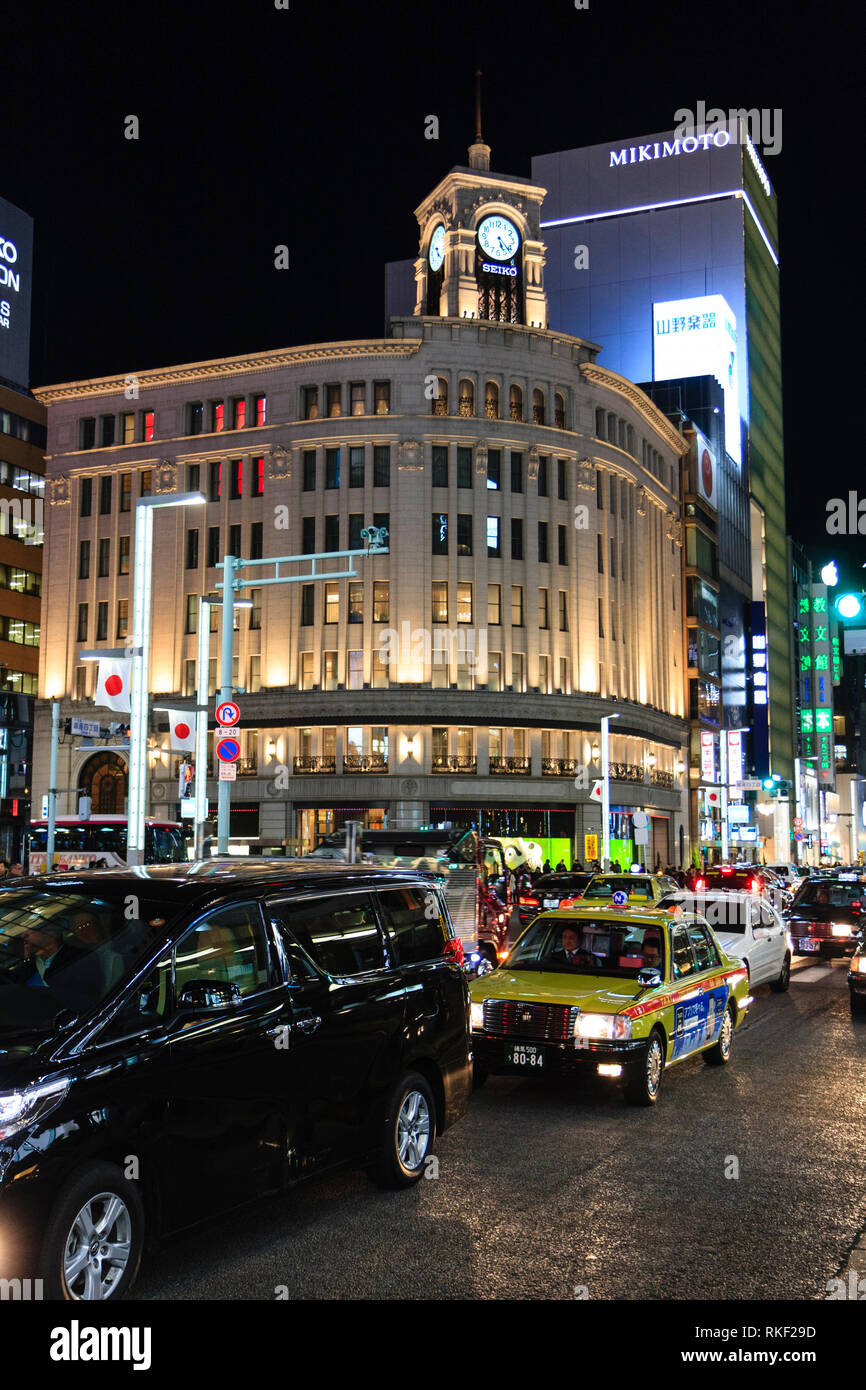 Tokyo, Ginza, night. 4-chome intersection with traffic and taxis passing by, with the landmark corner Wako Department store illuminated. Stock Photo
