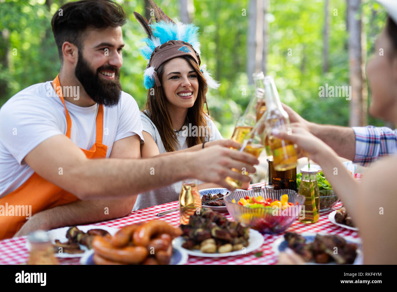 Group of happy friends eating and drinking beers at barbecue dinner