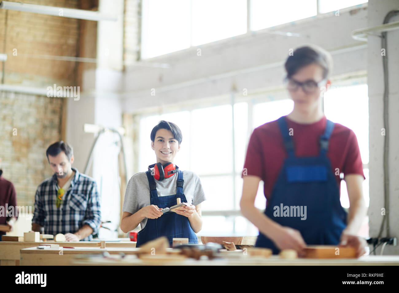 Cheerful lady working in carpentry shop Stock Photo
