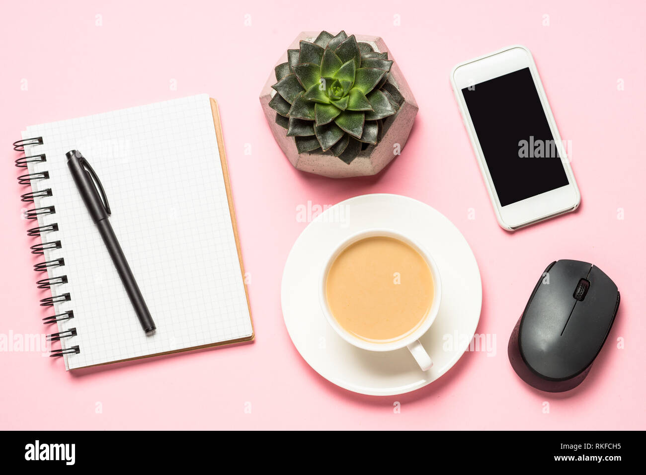 Freelance workplace with notepad, coffee cup, succulent and mouse on pink Stock Photo