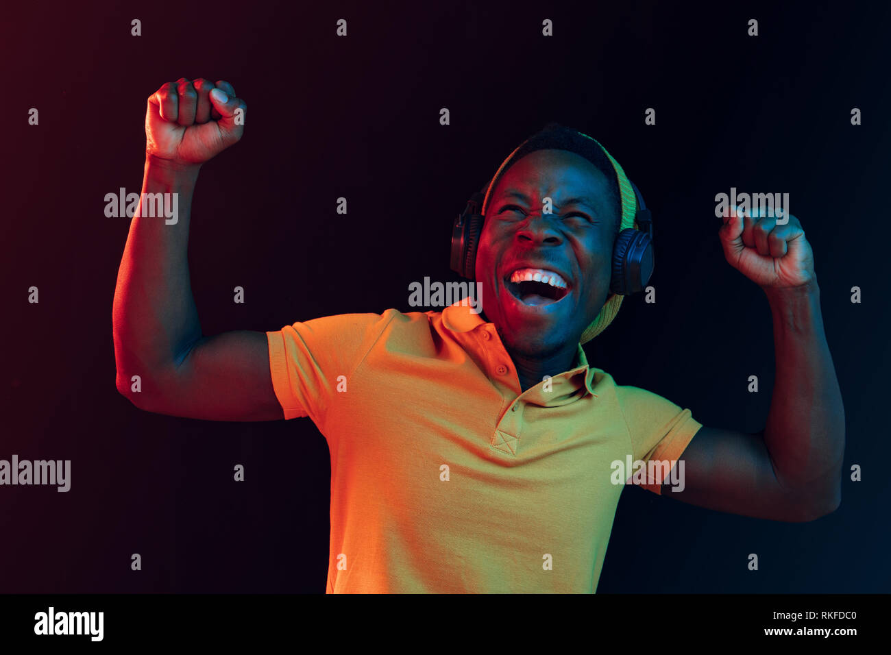 Young handsome happy hipster man listening music with headphones at