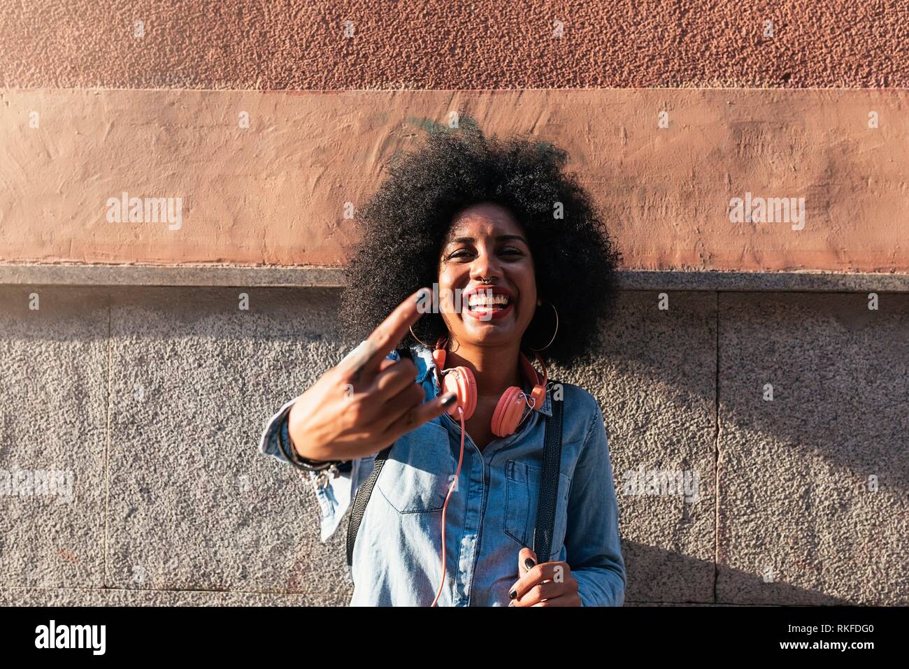 Beautiful afro american woman to throw up horns. Rebel expression. Stock Photo