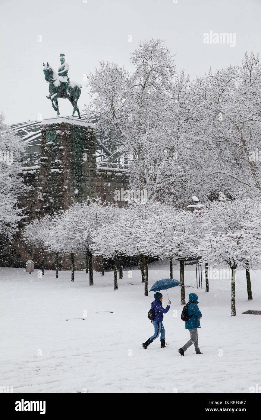 equestrian statue at the Hohenzollernbridge, women with umbrella on Franken square, snow, winter, Cologne, Germany.  Reiterdenkmal an der Hohenzollern Stock Photo