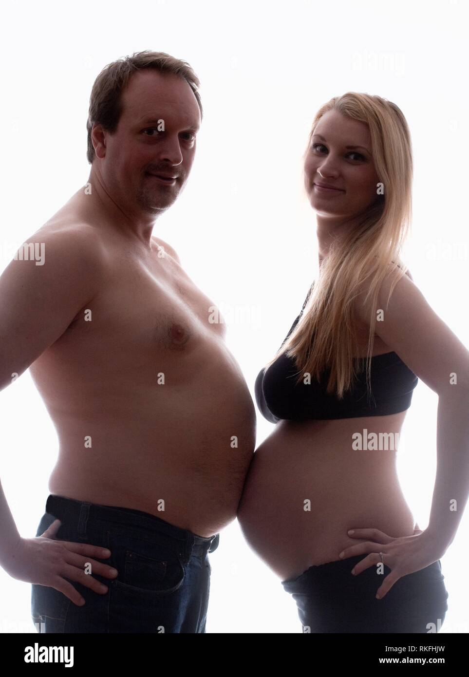 Pregnant Woman and her Partner Measuring Bellies. Stock Photo