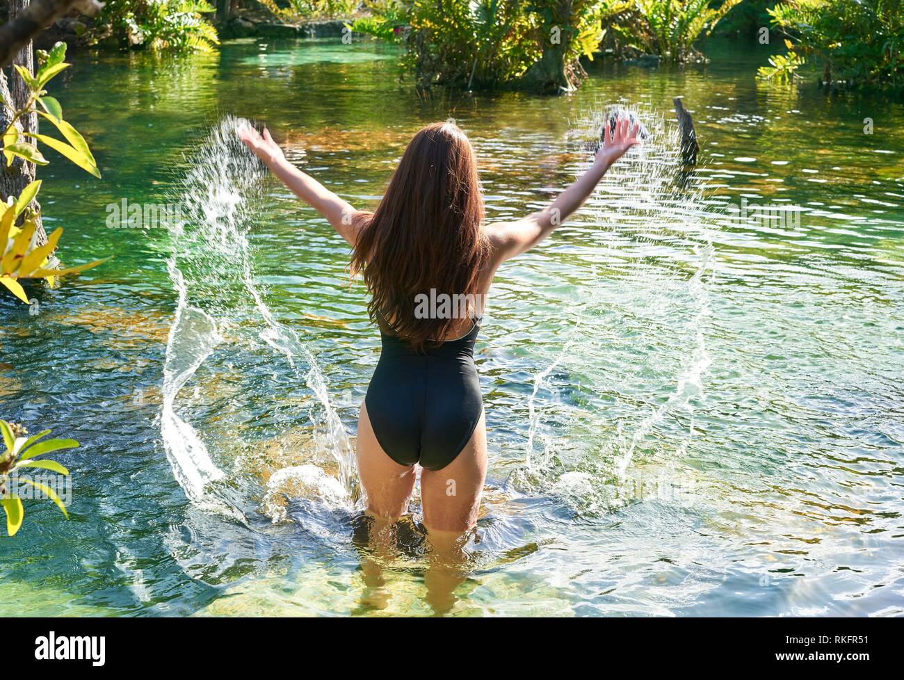 Beautiful teen girl in cenote of Riviera Maya splashing water with swimsuit. Stock Photo