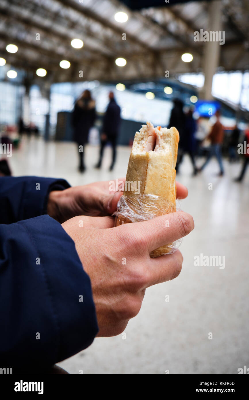 closeup of a caucasian man eating a sandwich in a train station or a ...