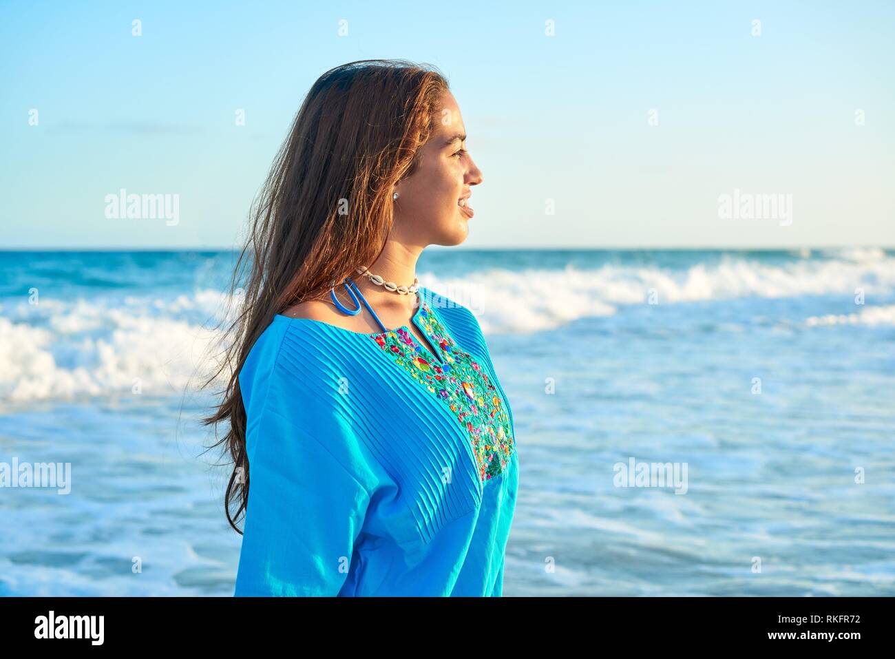Latin beautiful girl in Caribbean beach sunset with embroidery dress. Stock Photo